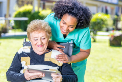 explaining tablet use to elder woman on wheelchair